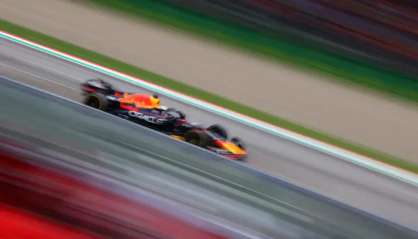 Ein Formel 1 Rennwagen rast über die Strecke, die Streifen von Rot und Grün verschwimmen. Ein Bild voller Dynamik, das die Geschwindigkeit und Aufregung des Rennsports einfängt.