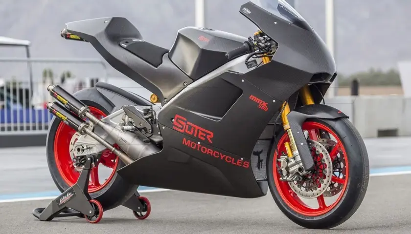 Schwarzes Suter MMX 500 Motorrad mit roten Felgen und Akrapovič Auspuffanlage auf einem Rennstreckenständer.