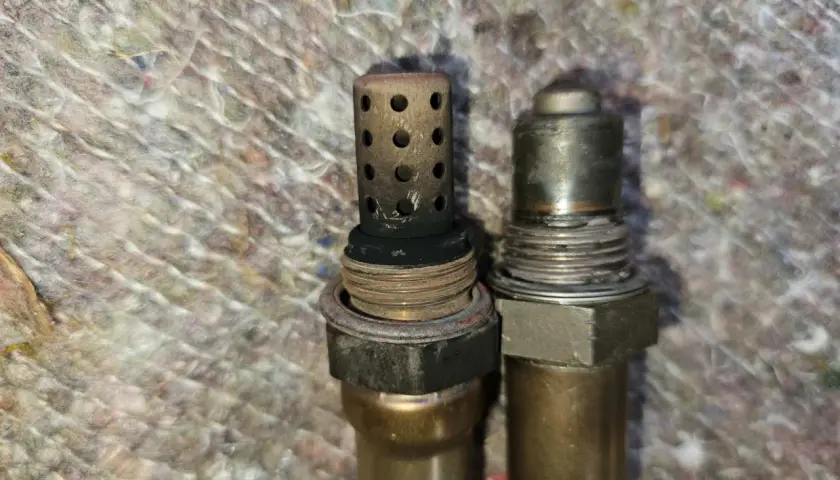 Zwei Lambdasonden, eine mit verrußtem Schutzgitter, möglicherweise Ursache für DTC P0420 bei Ford.