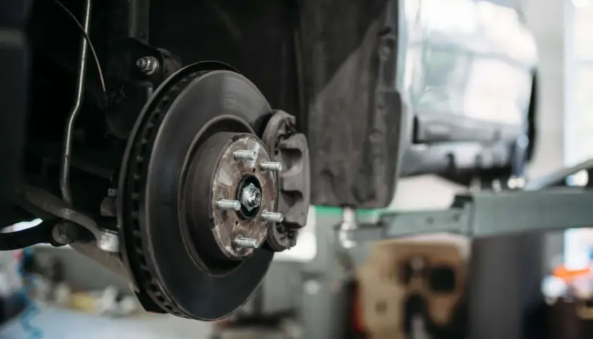 Detailaufnahme einer Autobremsanlage: Bremsscheibe, Bremssattel und Radnabe. So sieht eine Bremse aus, wenn sie für Wartungsarbeiten demontiert ist.