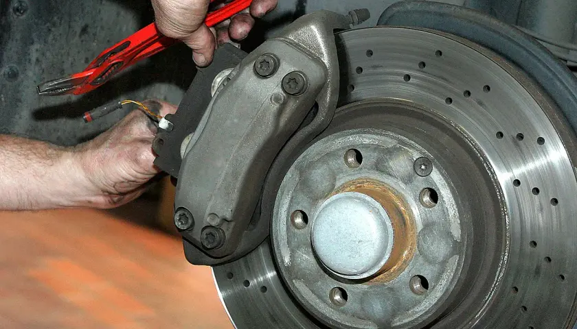 Mechaniker arbeitet an gelochter Bremsscheibe. Gute Quaro Bremsen Erfahrungen sind wichtig für die Sicherheit.
