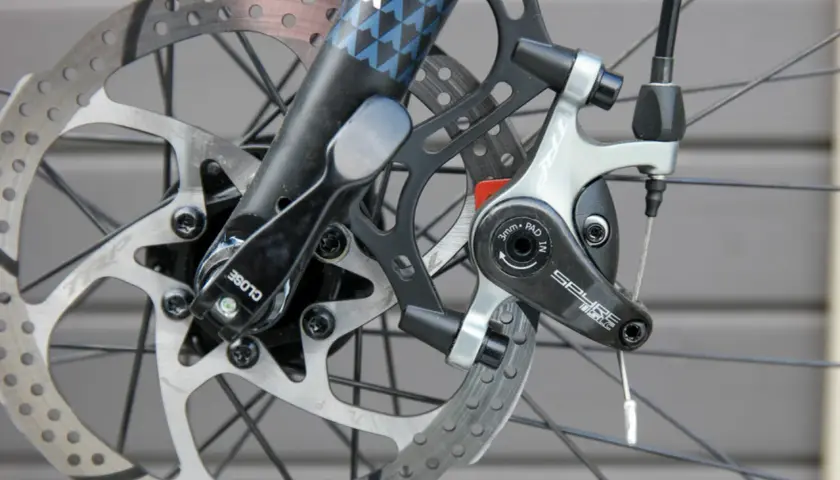 Nahaufnahme einer Fahrradbremse mit verschiedenen Arten von Bremsscheiben und einem TRP Spyre-Bremssattel.
