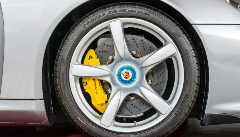 Silbernes Porsche-Rad mit gelben PCCB-Bremsen und perforierten Bremsscheiben.