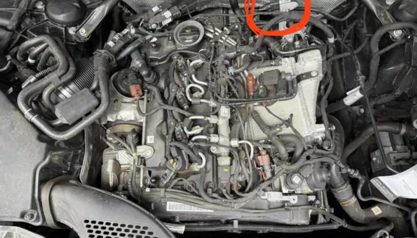 Motorraum eines Mercedes mit rotem Kreis um einen Sensor.