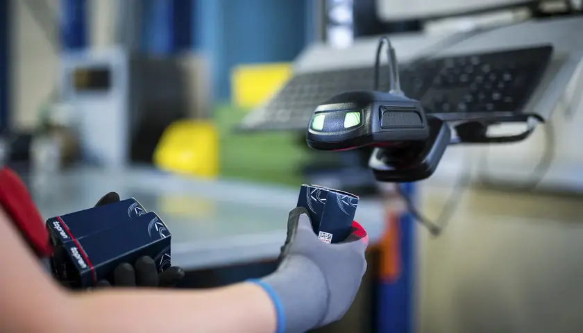 Hände mit Handschuhen halten Topran-Verpackungen unter einem Scanner. Gute Topran Erfahrungen im Lager.