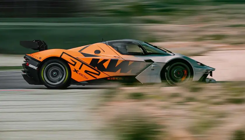 Orange-grauer KTM GT2-Sportwagen rast über die Rennstrecke, mit verschwommenem Hintergrund.