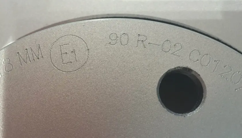 Nahaufnahme einer Bremsscheibe mit eingravierter Kennzeichnung "E1 90 R-02 C0120".