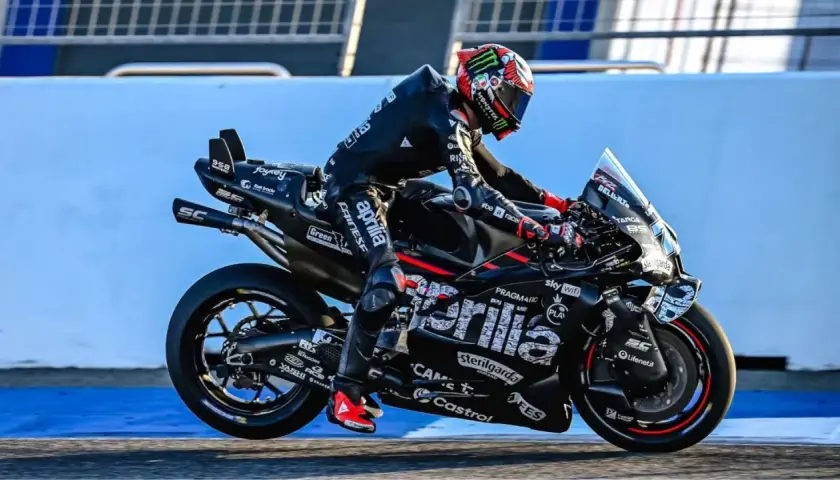 Marco Bezzecchi in voller Fahrt bei einem MotoGP-Rennen. Sein schwarzer Anzug und das Motorrad sind mit Sponsorenlogos bedeckt.