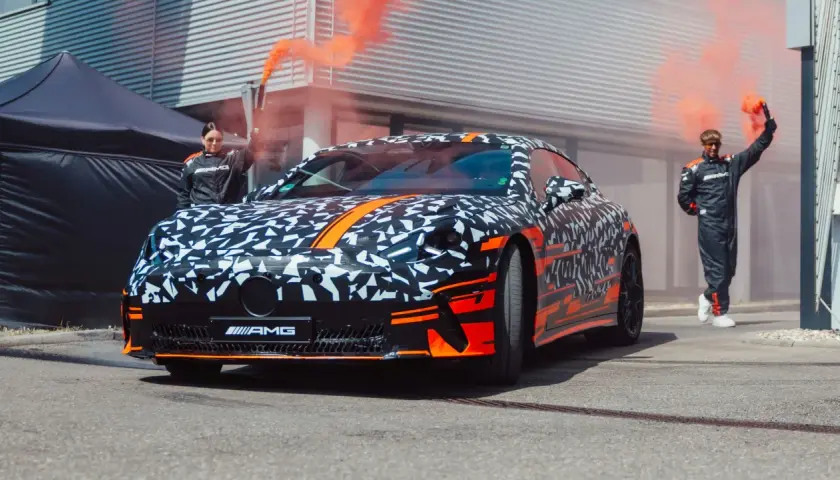Tarnkappen-AMG GT4 mit orangem Rauch und Rennfahrern.