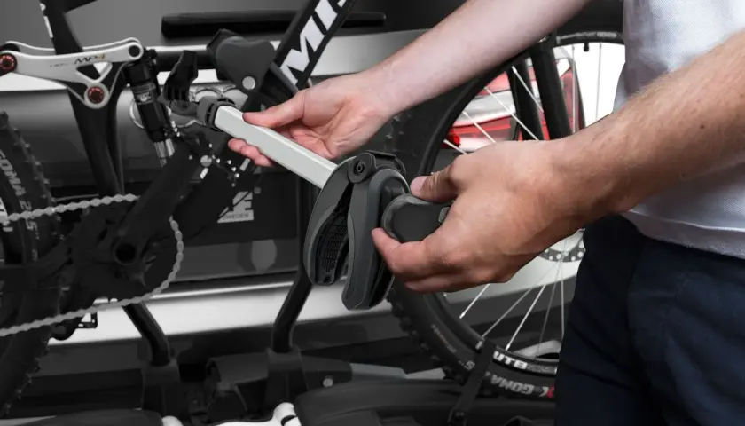 Hände montieren Fahrrad am Thule EasyFold XT 2. Ein Griff klemmt, was auf Thule EasyFold XT 2 Probleme hindeuten könnte.