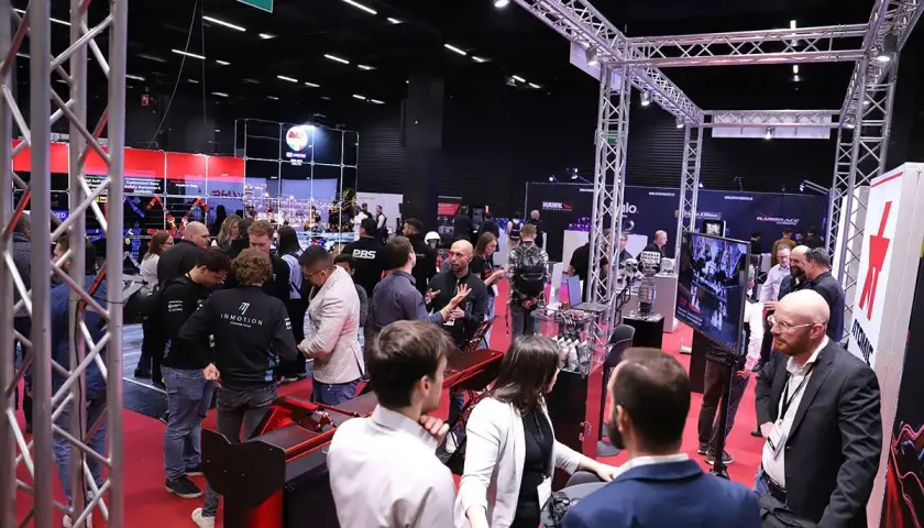 Besucher auf der Professional Motorsport World Expo, die sich über Rennsporttechnologie informieren.
