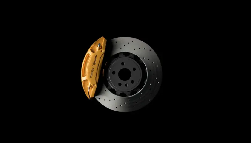 Goldener Bremssattel von Polestar/Brembo auf gelochter Bremsscheibe. So funktioniert eine Bremse: Reibung stoppt das Fahrzeug.