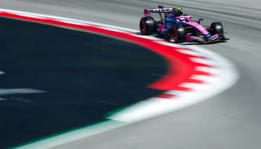 Ein Formel-1-Auto in Pink und Blau rast über die Rennstrecke. Dieses Bild fängt die Dynamik des Motorsports im TV perfekt ein.