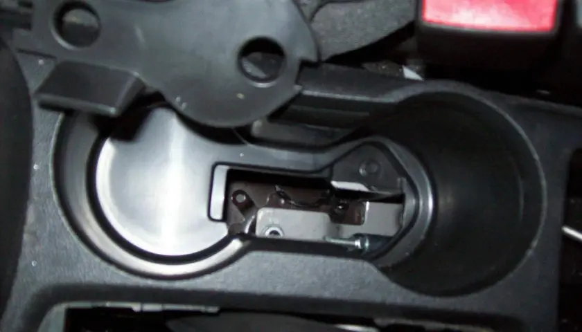 Detailaufnahme des Innenraums eines Opel Mokka, Fokus auf den Bereich um den Getränkehalter, wo das Handbremsseil gewechselt wird.