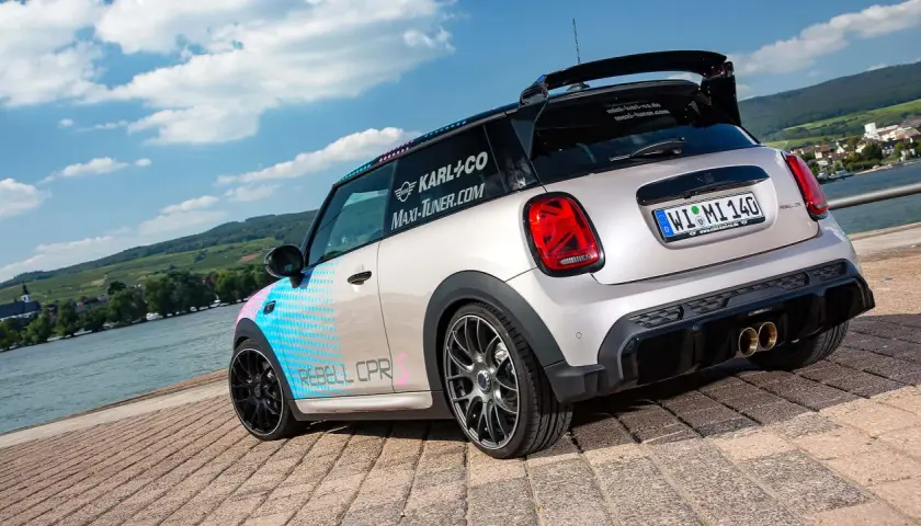 Ein getunter Mini F56 mit auffälligem Design und Sportauspuff steht am Wasser.
