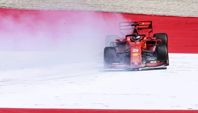 Ein roter Formel 1 Ferrari mit der Startnummer 5 bremst stark ab und erzeugt viel Rauch. Ein Formel 1 Auto verbraucht enorm viel Kraftstoff.