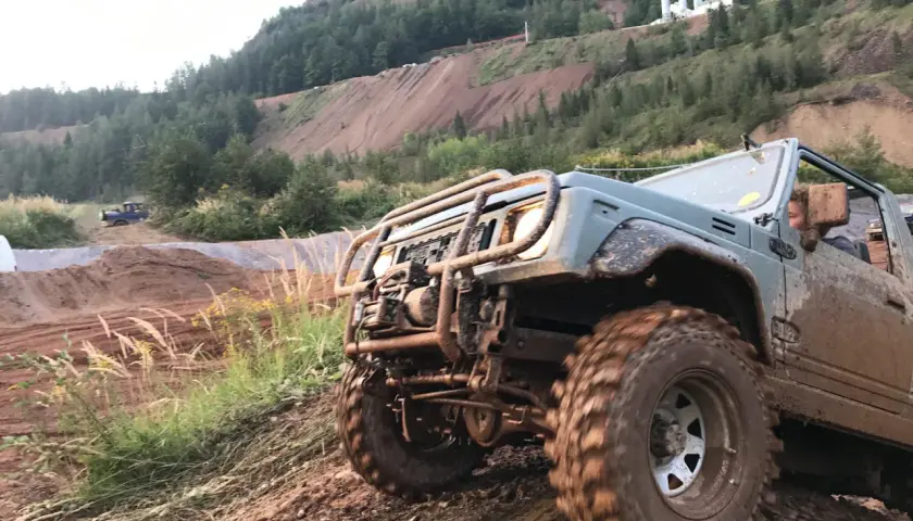 Schlammiges Geländefahrzeug kämpft sich bergauf. Die 4wd bedeutung wird hier deutlich: Allradantrieb für extreme Bedingungen.