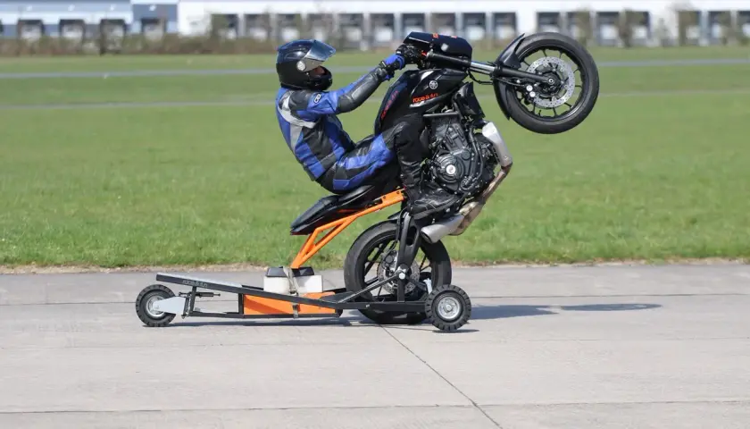 Motorradfahrer übt einen Wheelie auf einem Trainingsständer.