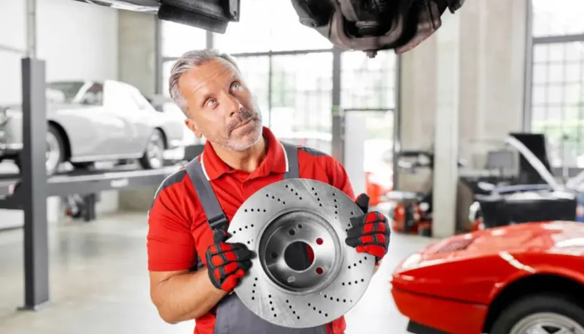 Mechaniker hält Bremsscheibe, gute febi bremsen erfahrung. Auto in Werkstatt.