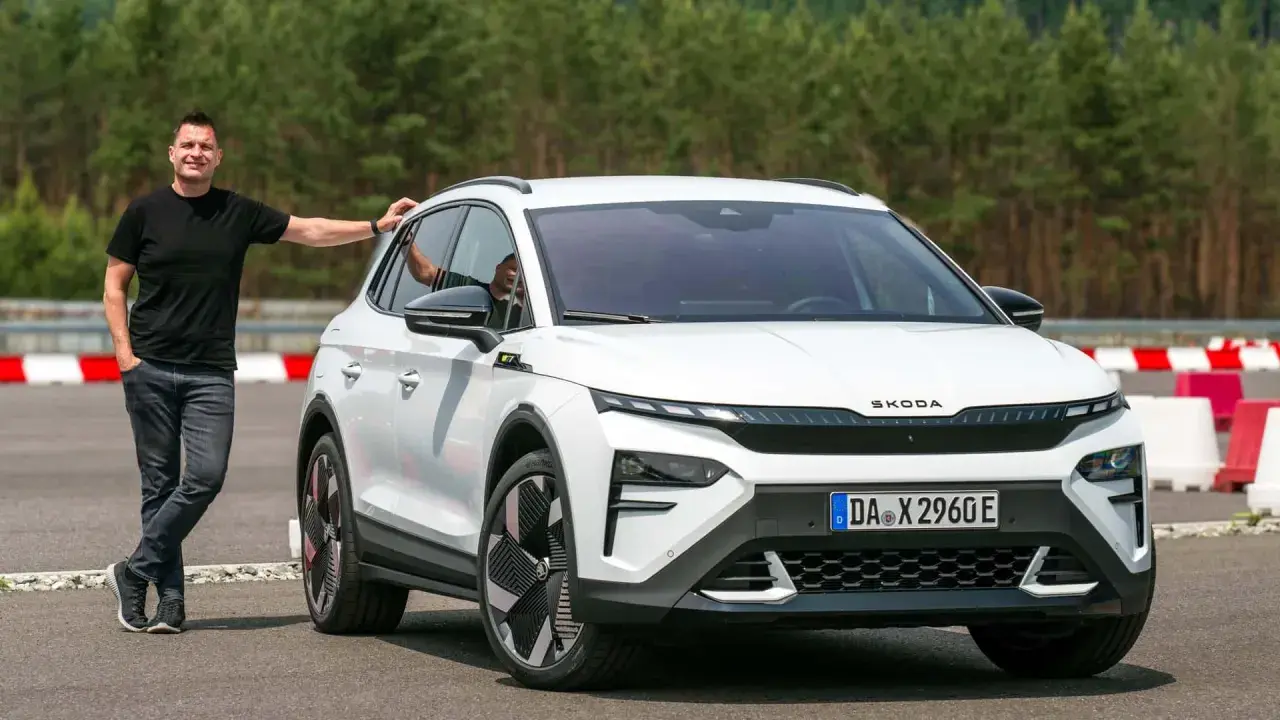 Mann lehnt an weißem Skoda Enyaq RS. Was heist RS? Sportlichkeit und Leistung, die man hier sieht.