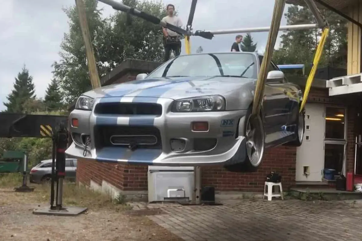 Der ikonische Paul Walker Nissan Skyline R34, bekannt aus "Fast & Furious", wird von einem Kran angehoben.
