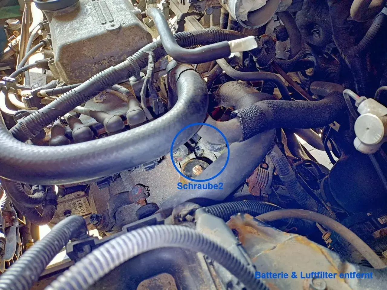 Motorraum eines Hyundai i30. Die Batterie und der Luftfilter sind entfernt. Eine Schraube am Anlasser ist markiert.