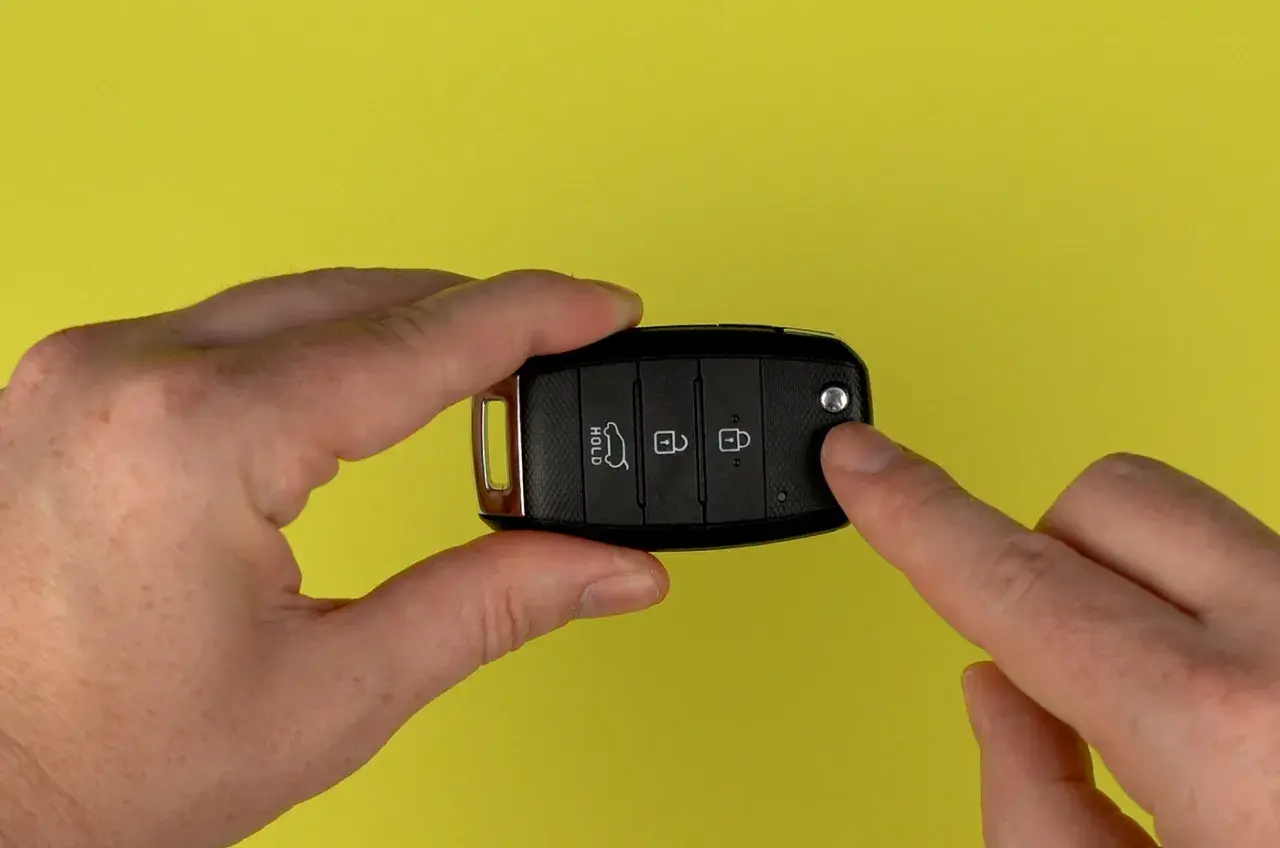 Hände halten Autoschlüssel für Kia Sportage, um die Batterie zu wechseln.