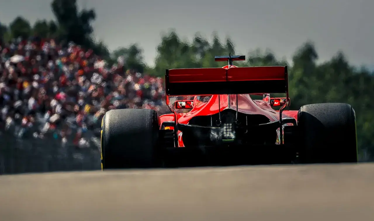 Ein roter Formel 1 Bolide rast auf die Tribüne zu. Man fragt sich, wie viel PS ein Formel 1 Auto hat, wenn es so schnell ist.