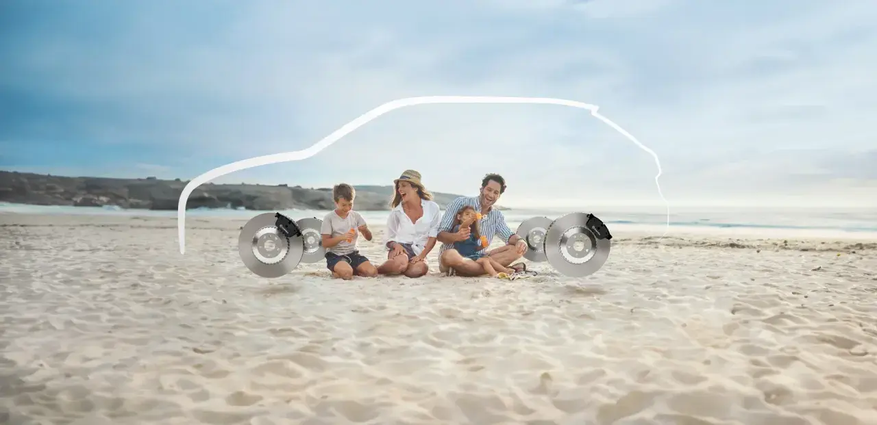 Familie am Strand sitzt neben Bremsscheiben, mit einer weißen Autokontur darüber.