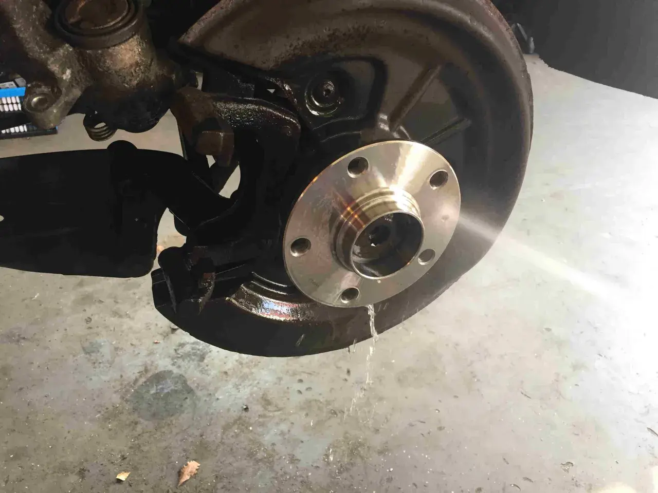 Radnabe eines Golf 5, bereit für den Wechsel des vorderen Radlagers. Flüssigkeit tropft auf den Boden.