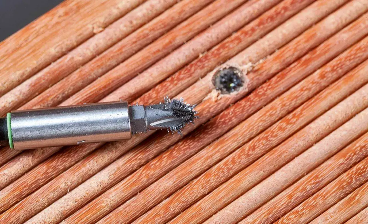 Ein Schraubenextraktor mit Metallspänen auf Holzoberfläche.