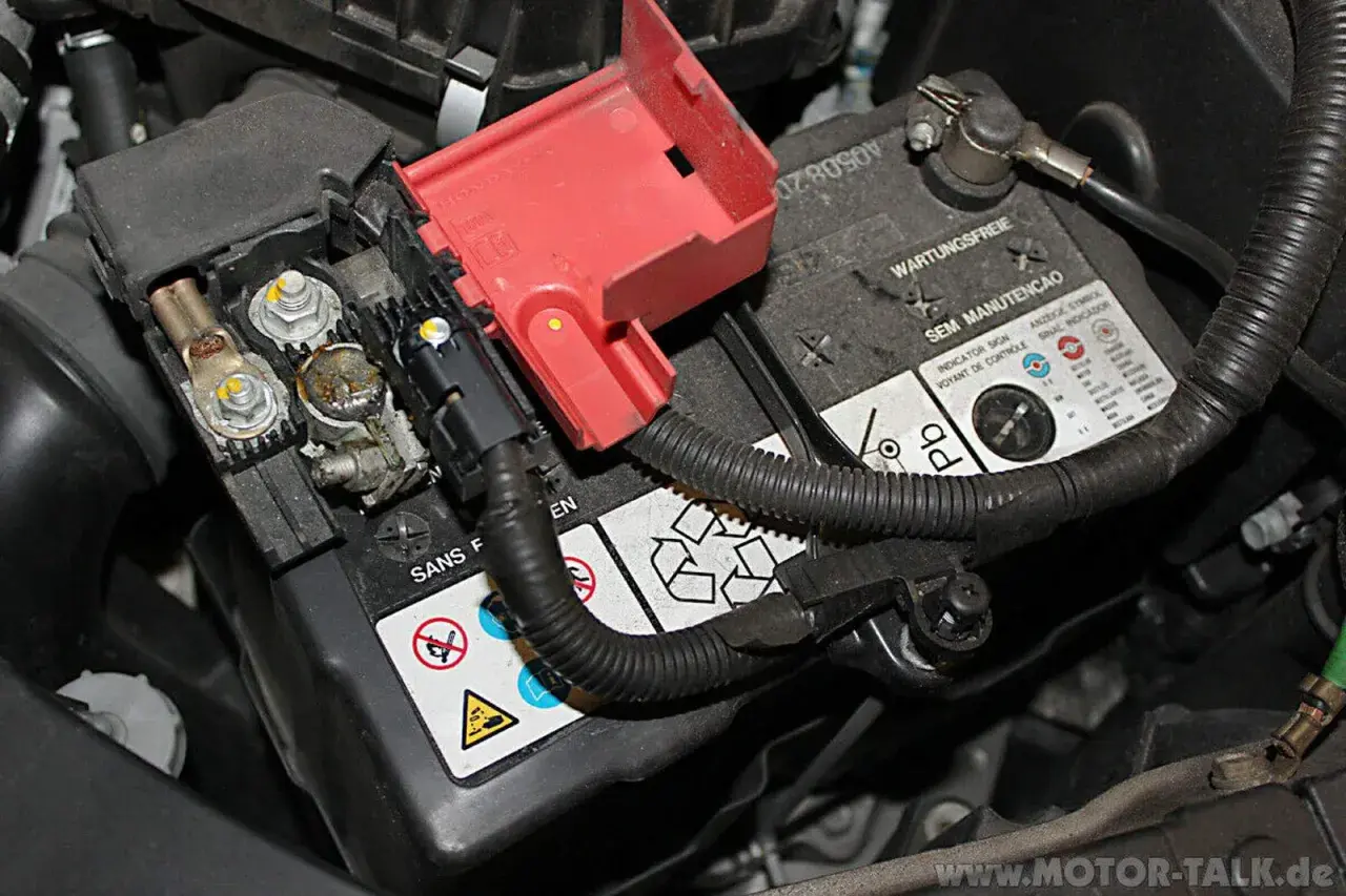Batteriepole eines Honda Jazz, bereit für den Wechsel. Die roten Abdeckungen sind abgenommen, die Kabelanschlüsse sichtbar.