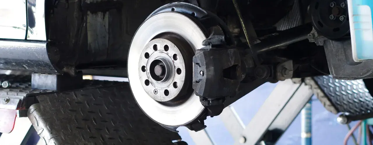 Nahaufnahme einer Bremsscheibe aus Metall, die an einem Auto montiert ist. Das Material der Bremsscheibe ist robust und für hohe Temperaturen ausgelegt.