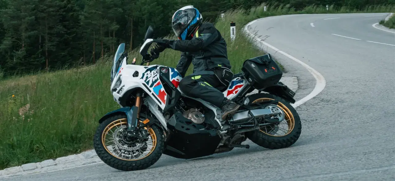 Motorradfahrer mit Helm und Ausrüstung nimmt eine Kurve, der Lenkimpuls des Motorrads ist deutlich zu sehen.