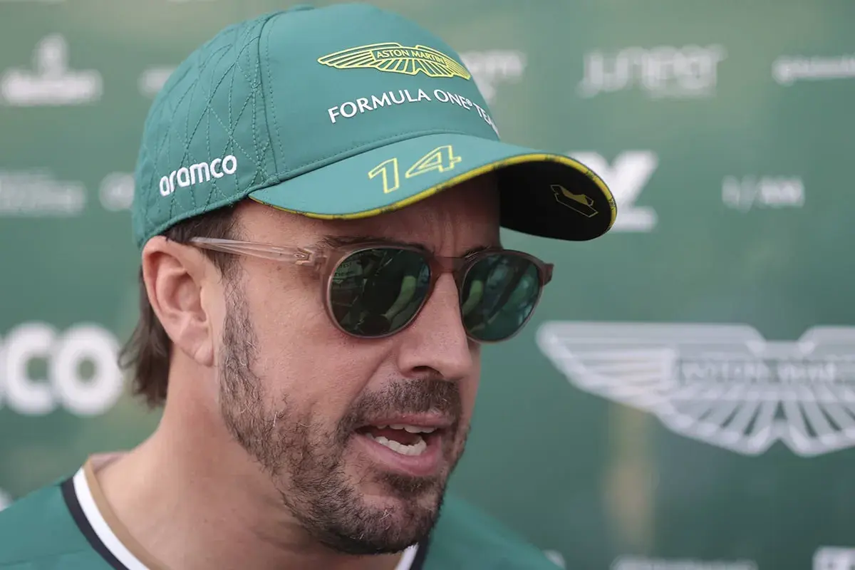 Fernando Alonso trägt eine Aston Martin Kappe und Sonnenbrille. Sein Gehalt bei Aston Martin ist ein heiß diskutiertes Thema.