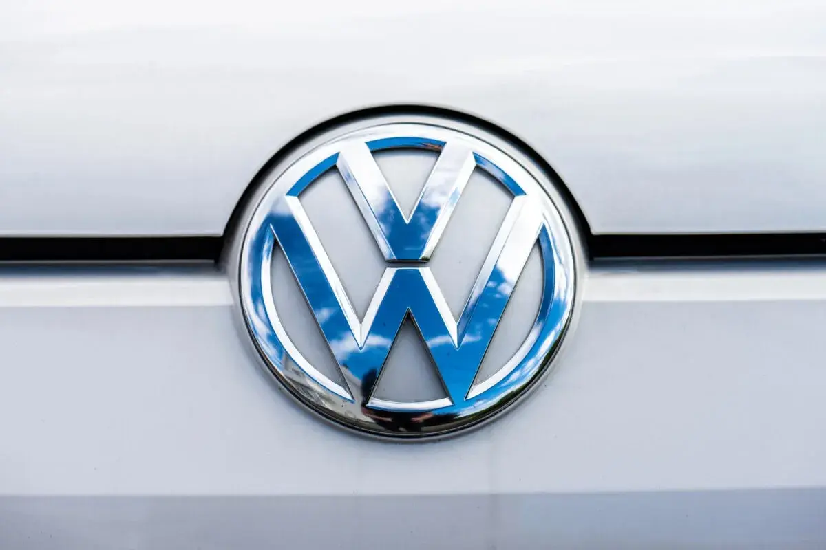 Das glänzende VW-Logo auf dem silbernen Lack reflektiert den blauen Himmel mit Wolken. Ein p0016 vw.