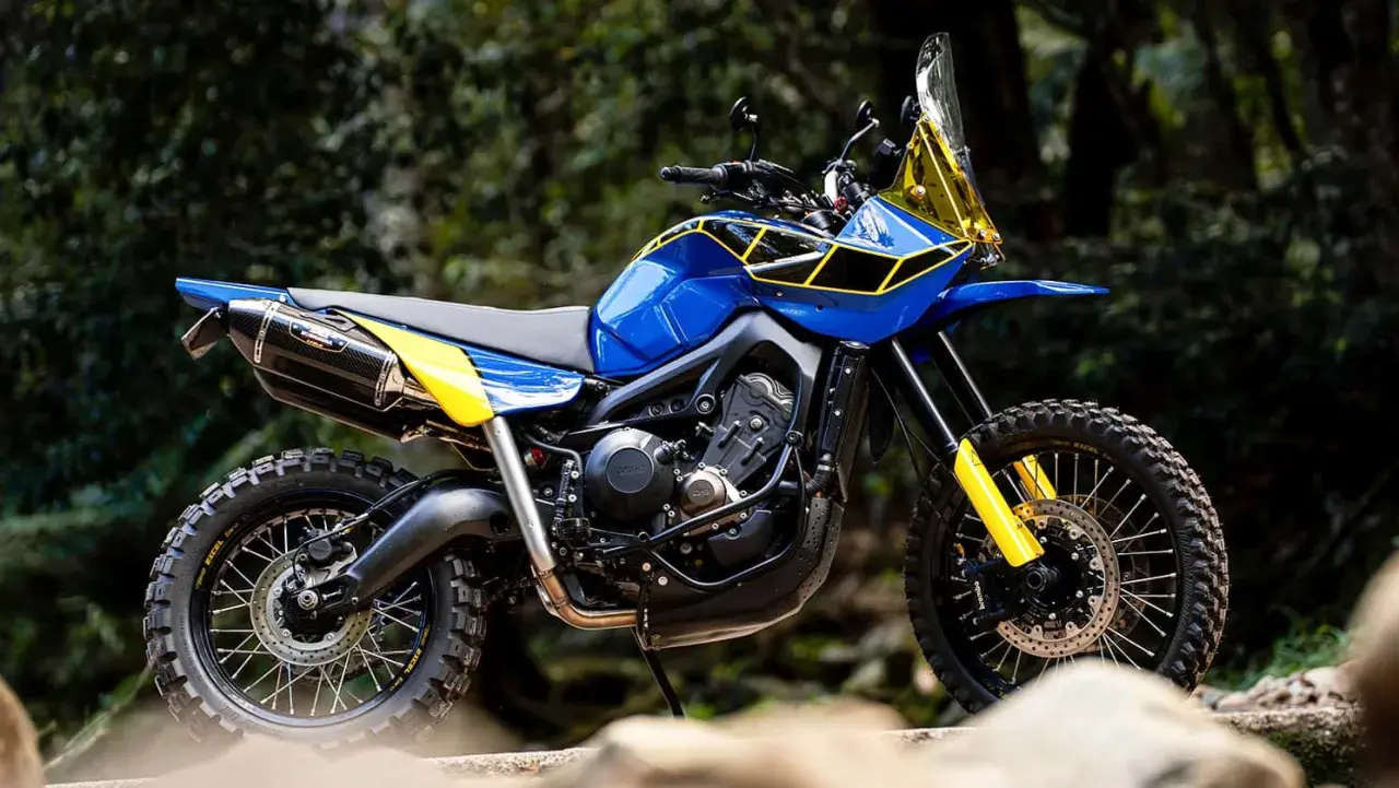 Eine blaue Yamaha Ténéré mit gelben Akzenten und Offroad-Reifen steht im Freien.