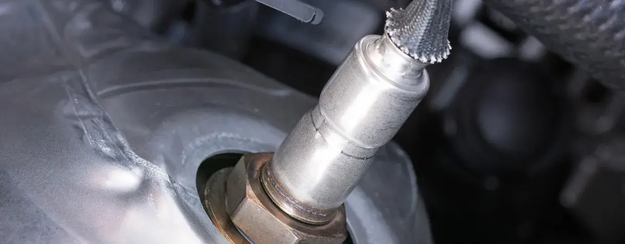 Nahaufnahme einer Lambdasonde, die in ein metallisches Bauteil eingeschraubt ist.