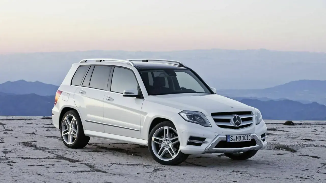 Weißer Mercedes GLK steht auf felsigem Untergrund vor bergiger Kulisse.