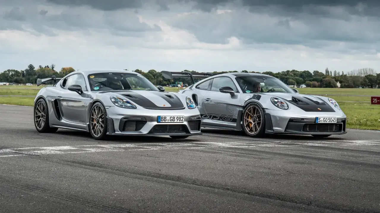 Zwei silberne Porsche GT4 und GT4 RS stehen nebeneinander auf einer Rennstrecke.