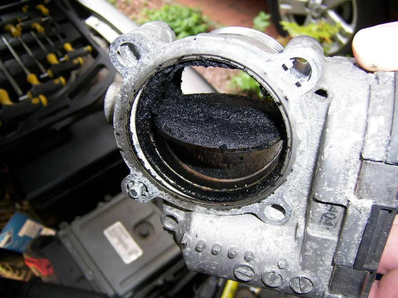 Stark verschmutztes AGR-Ventil eines Volvo XC60, bereit zum Ausbau. Rußablagerungen blockieren den Durchgang.