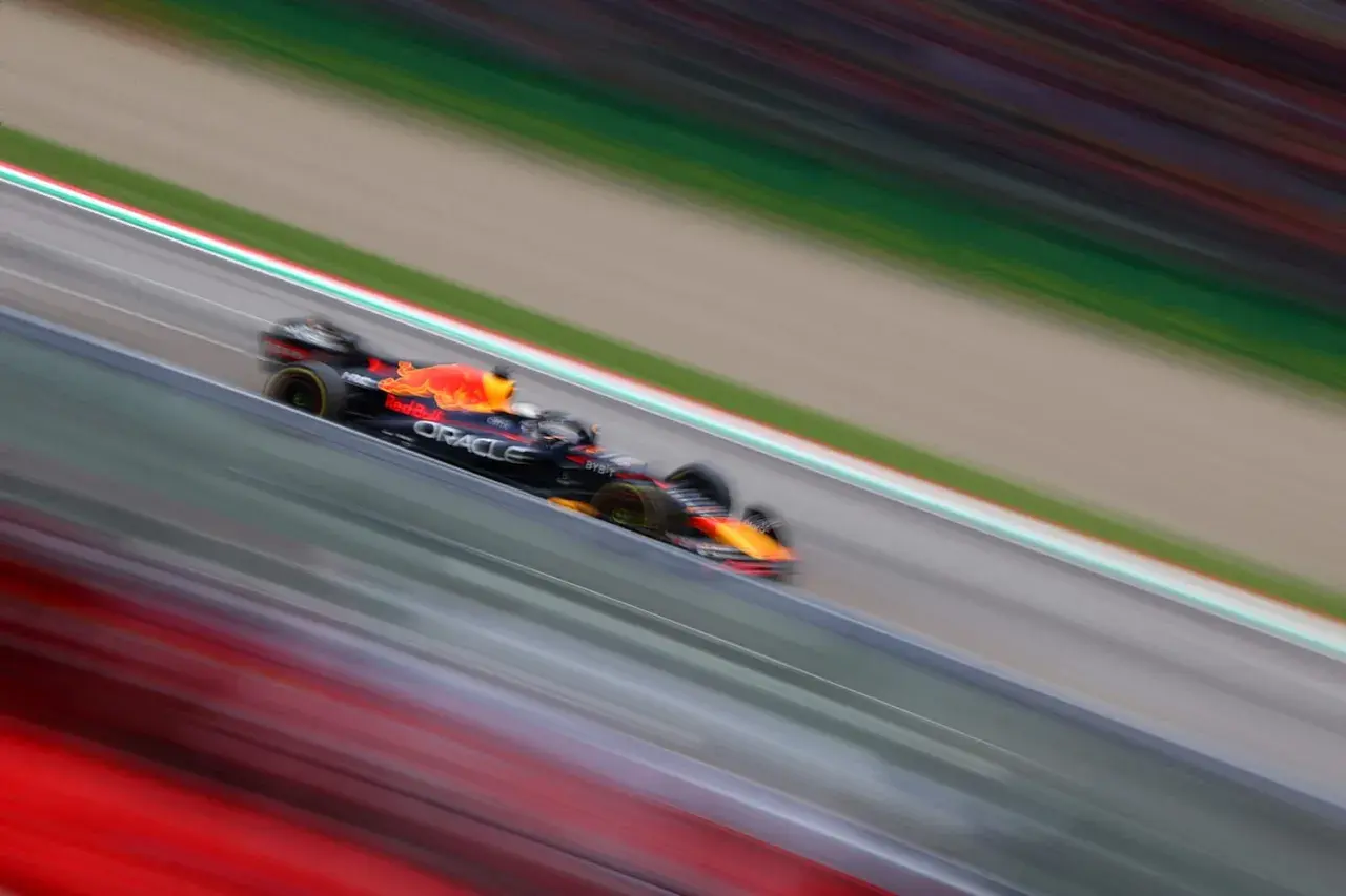 Ein Formel 1 Rennwagen rast über die Strecke, die Streifen von Rot und Grün verschwimmen. Ein Bild voller Dynamik, das die Geschwindigkeit und Aufregung des Rennsports einfängt.