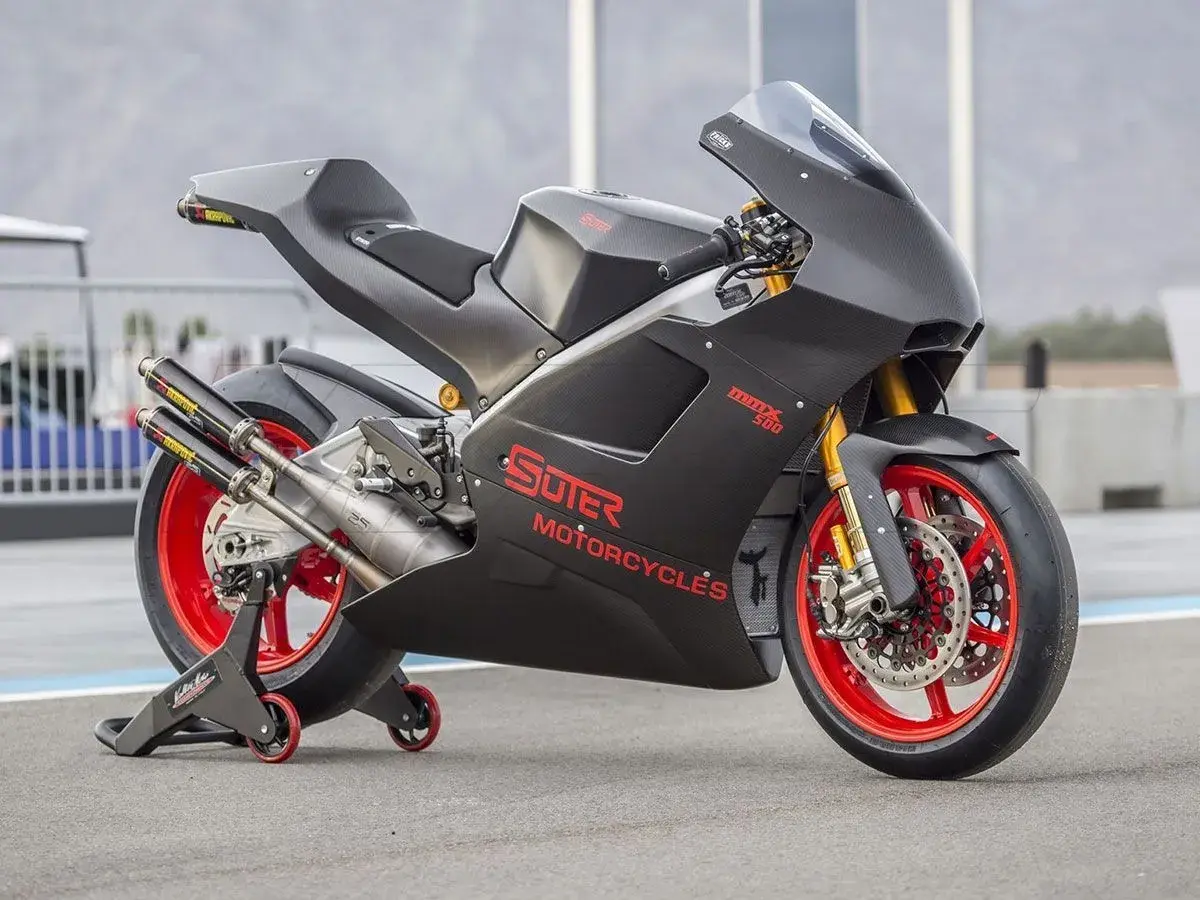Schwarzes Suter MMX 500 Motorrad mit roten Felgen und Akrapovič Auspuffanlage auf einem Rennstreckenständer.