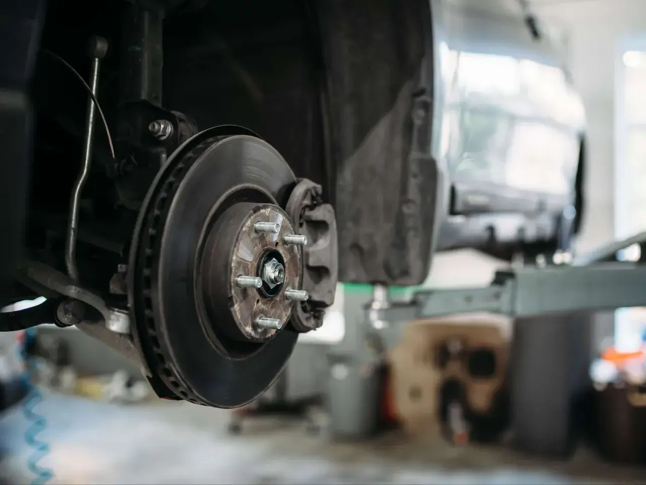 Detailaufnahme einer Autobremsanlage: Bremsscheibe, Bremssattel und Radnabe. So sieht eine Bremse aus, wenn sie für Wartungsarbeiten demontiert ist.