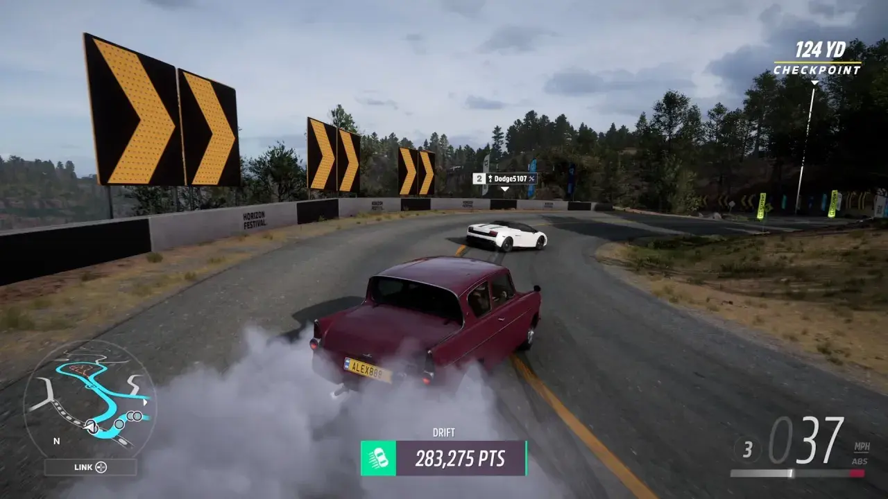 Ein roter Oldtimer driftet auf einer Rennstrecke, umgeben von Bäumen und Warnschildern. Man kann mit Allrad driften, um Punkte zu sammeln.