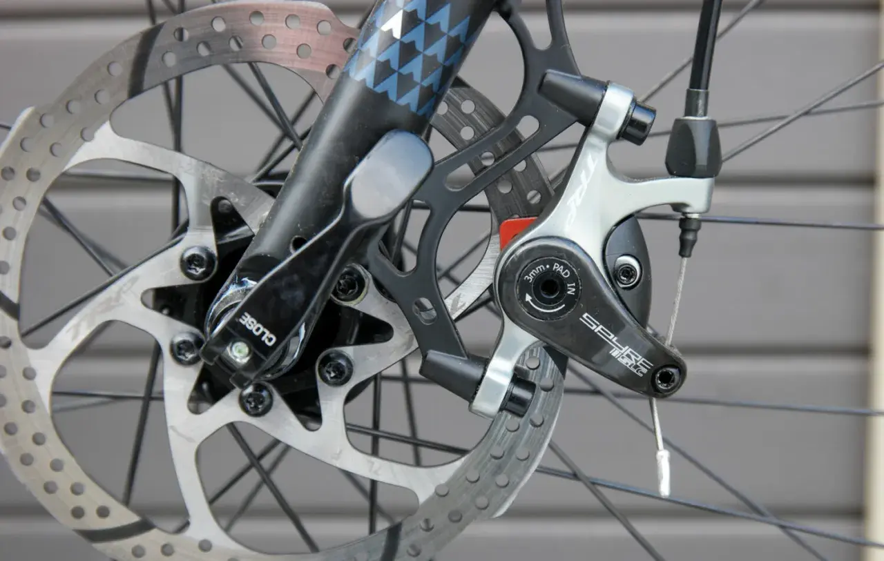 Nahaufnahme einer Fahrradbremse mit verschiedenen Arten von Bremsscheiben und einem TRP Spyre-Bremssattel.