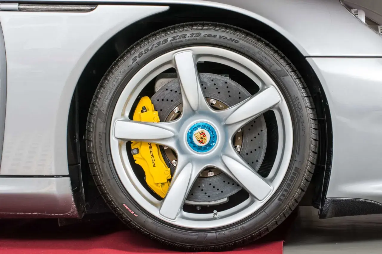 Silbernes Porsche-Rad mit gelben PCCB-Bremsen und perforierten Bremsscheiben.