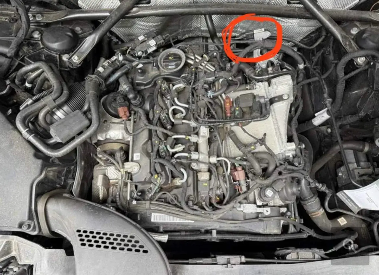 Motorraum eines Mercedes mit rotem Kreis um einen Sensor.