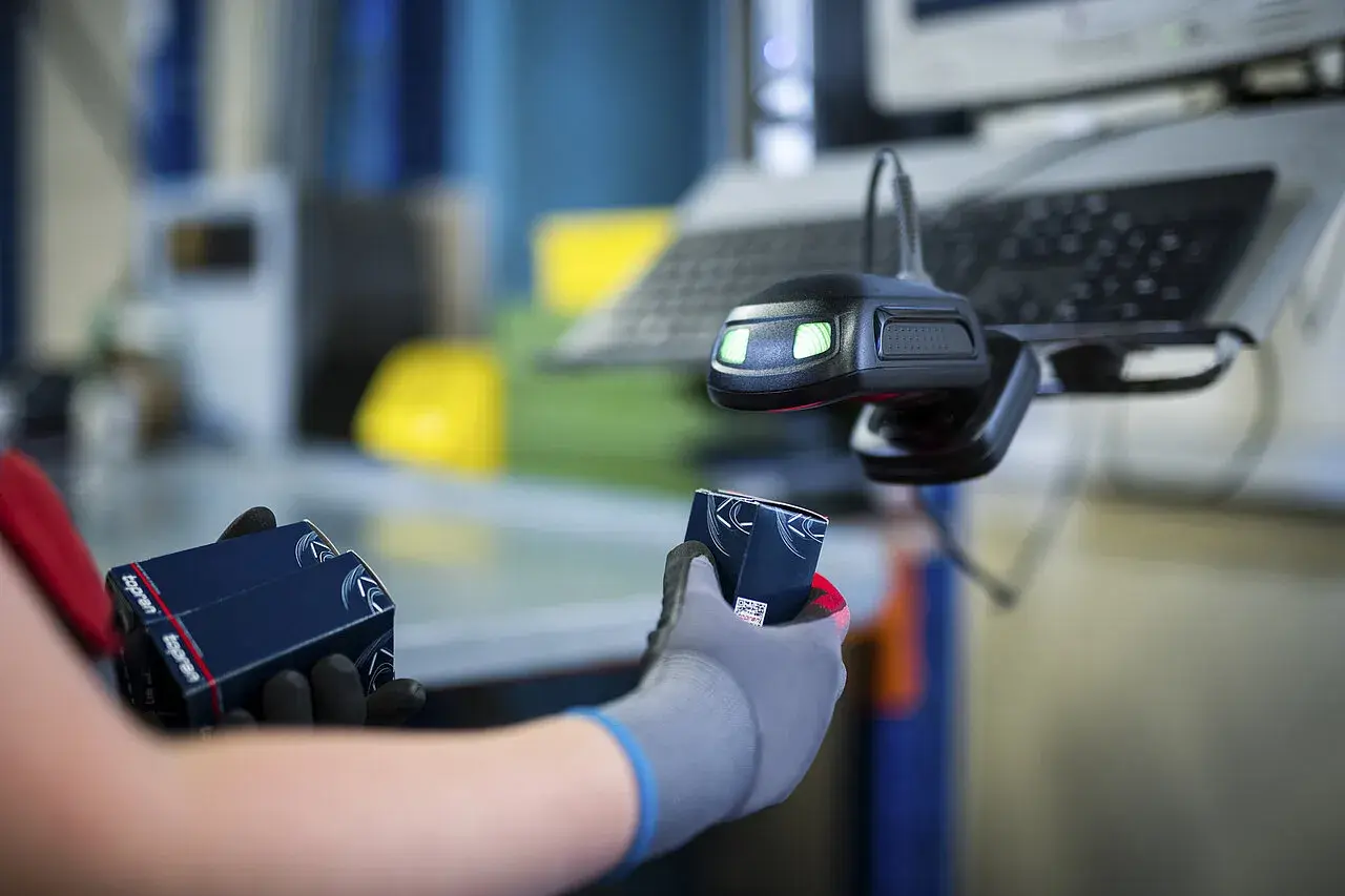Hände mit Handschuhen halten Topran-Verpackungen unter einem Scanner. Gute Topran Erfahrungen im Lager.
