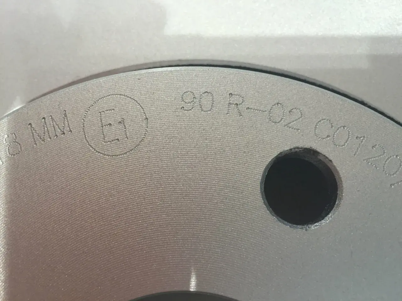 Nahaufnahme einer Bremsscheibe mit eingravierter Kennzeichnung "E1 90 R-02 C0120".